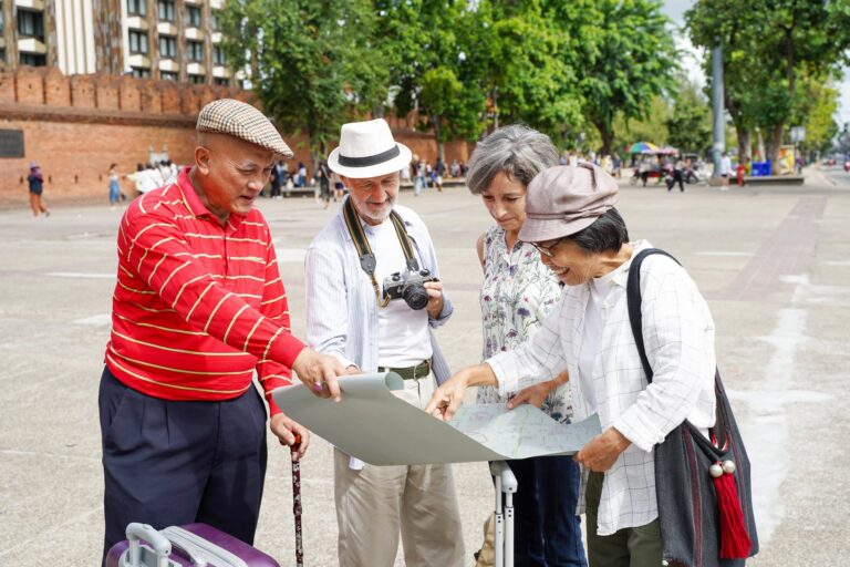 Four older travelers reading a city map together in a town square